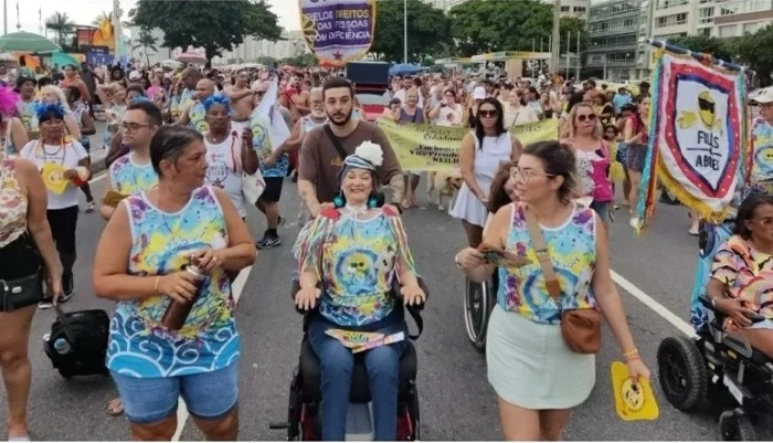 Registro jornalístico de pessoas com deficiência e apoiadores participando do Foliões da ABRACES em Copacabana, em 2024